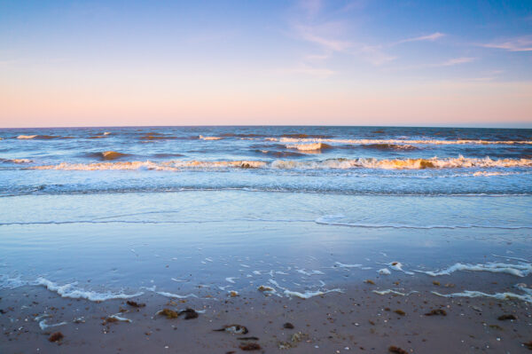 The evening sun softly lit the ocean, painted the waves in orange-pink colors.