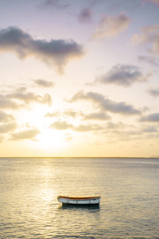 Beautiful sunset light softly illuminated a little boat floating along a shore in Bonaire.