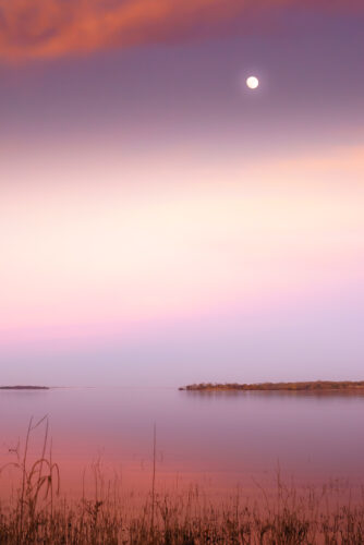 A moon was softly shining in twilight, creating a dreamy atmosphere at Lake Somerville, Texas.