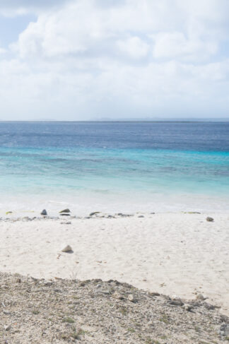 The beautiful Caribbean ocean was seen under hazy white clouds on a sandy beach in Bonaire, Dutch Caribbean.