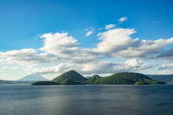 Nakajima island and Mount Yotei were seen from the shore of Lake Toya after a rainy cloudy day in June, 2018.