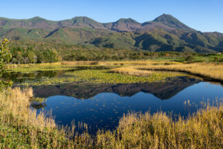A beautiful reflection of Shiretoko mountains is seen at Shiretoko Goko (Five Lakes) in autumn colors in Hokkaido Japan.